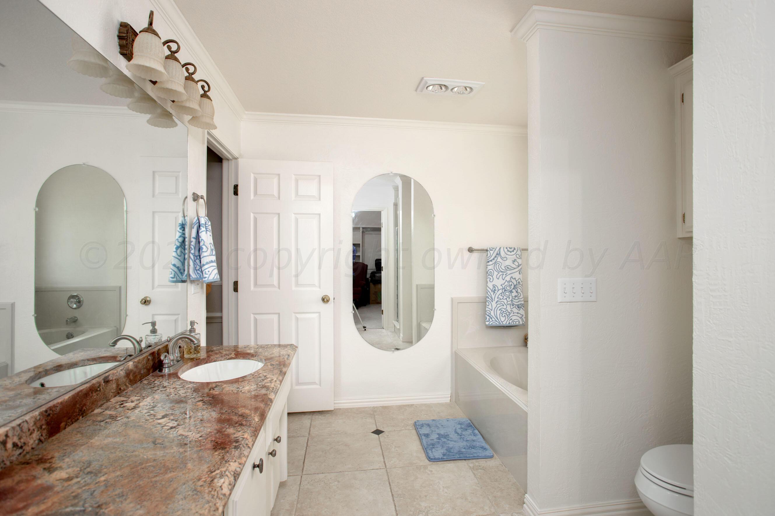 7301 Smoketree Drive Amarillo, TX 79124 - Photo 21 of 37 a spacious bathroom with a granite countertop sink a toilet a mirror and vanity