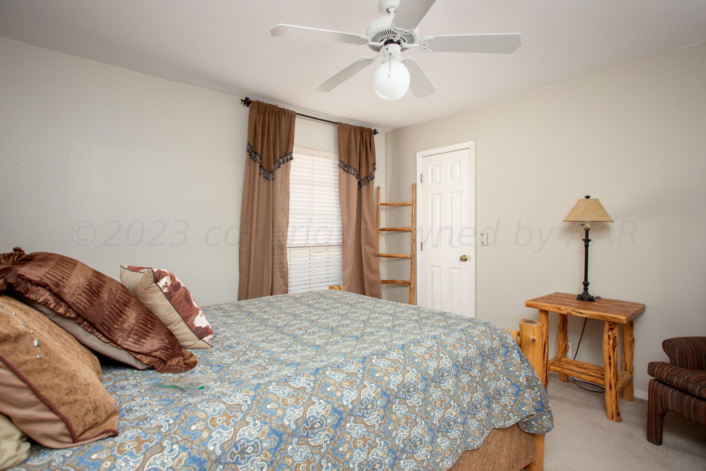 7301 Smoketree Drive Amarillo, TX 79124 - Photo 25 of 37 a bedroom with a bed and a chandelier