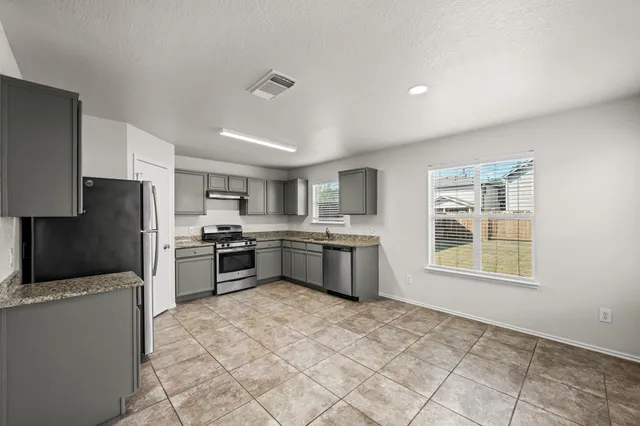 a kitchen with stainless steel appliances granite countertop a stove top oven a sink a refrigerator and a granite counter tops