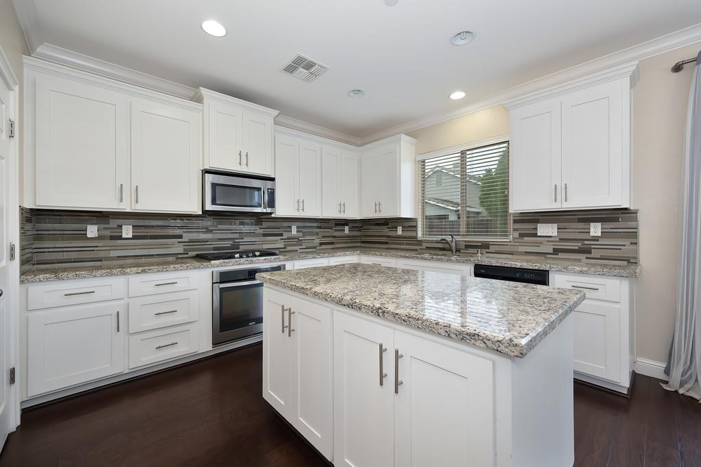 1916 Hartsfield Way Lincoln, CA 95648 - Photo 9 of 35 a kitchen with stainless steel appliances granite countertop a stove a sink dishwasher and a microwave oven with white cabinets