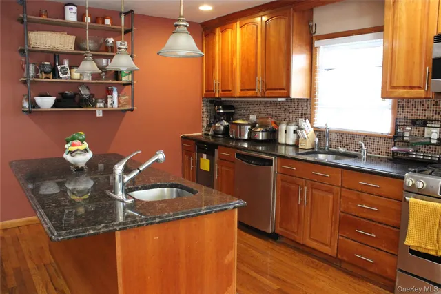 a kitchen with stainless steel appliances granite countertop a sink a stove cabinets and a counter top space