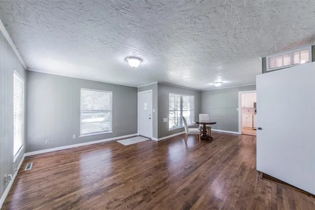 a view of an empty room with a window and wooden floor