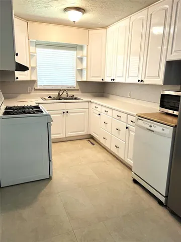 a kitchen with granite countertop white cabinets and white appliances