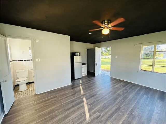a view of an empty room with window and wooden floor