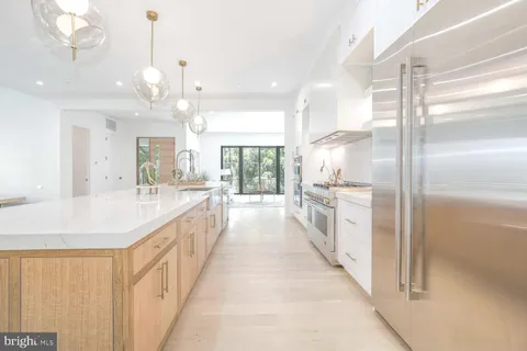 a large white kitchen with granite countertop a stove and large cabinets
