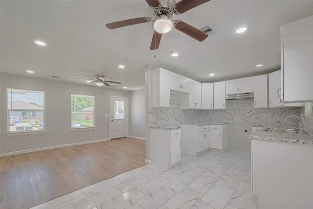 a large kitchen with granite countertop a stove a sink a window and dining table