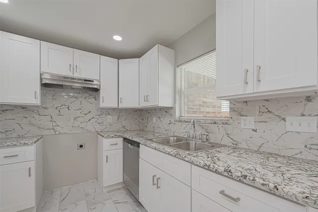 a kitchen with granite countertop white cabinets and a sink
