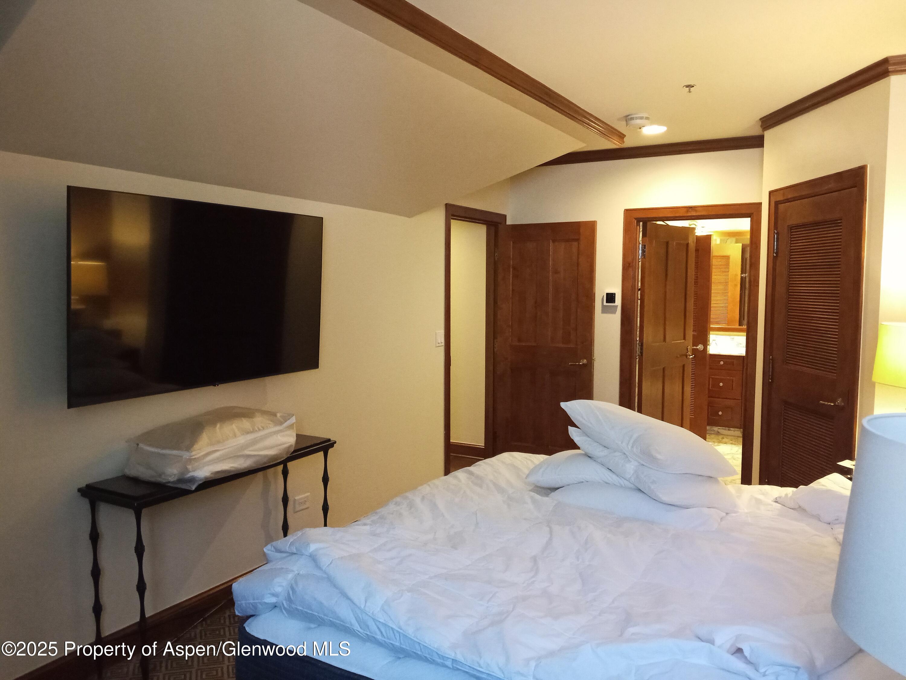 75 Prospector Road, Unit 8204 WINTER INTEREST #5 Aspen, CO 81611 - Photo 33 of 41 a bedroom with a bed and a flat screen tv