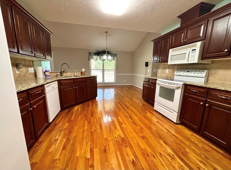 205 Morton Court Fortson, GA 31808 - Photo 6 of 23 a kitchen with granite countertop wooden floors and stainless steel appliances