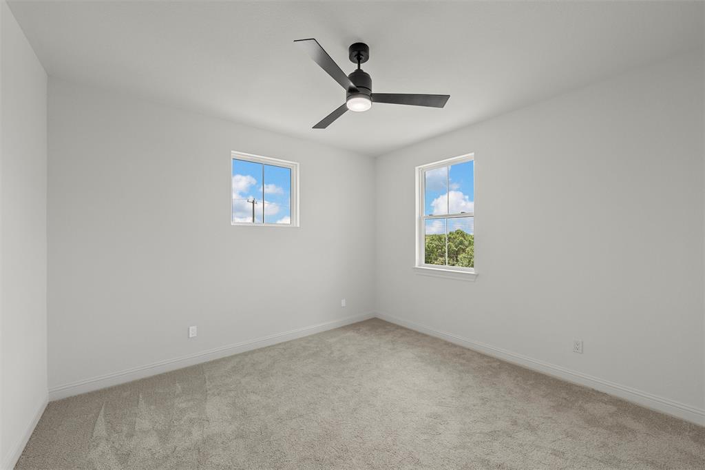 20 Ritchie Road Woodway, TX 76712 - Photo 23 of 40 Neutral wall paint, carpeted flooring, two windows, and a ceiling fan with integrated lighting