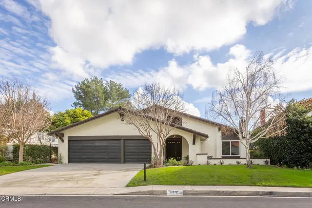 a front view of a house with a garden and trees
