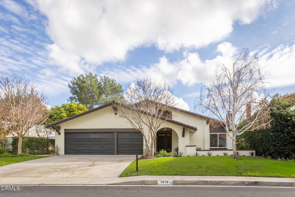 a front view of a house with a garden and trees