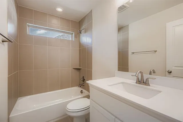 a bathroom with a bathtub shower sink vanity mirror and toilet