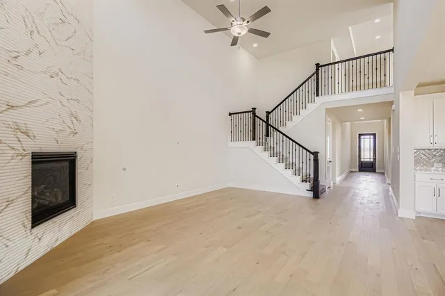 a view of a livingroom with wooden floor a ceiling fan and staircase