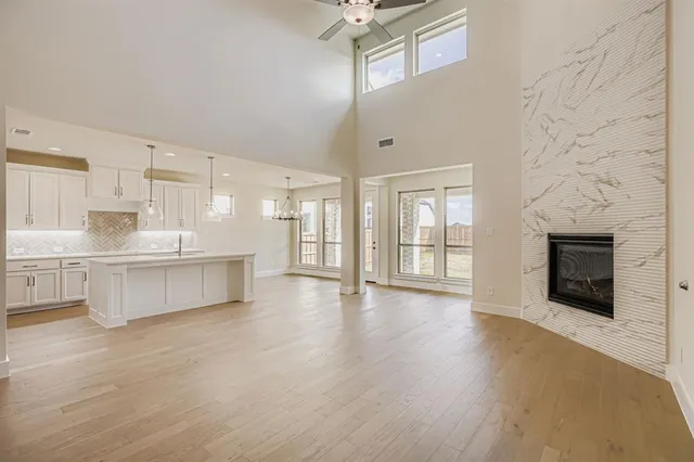 a large white kitchen with granite countertop a stove top oven a sink and a fireplace with wooden floor