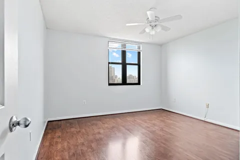 an empty room with a chandelier fan and windows