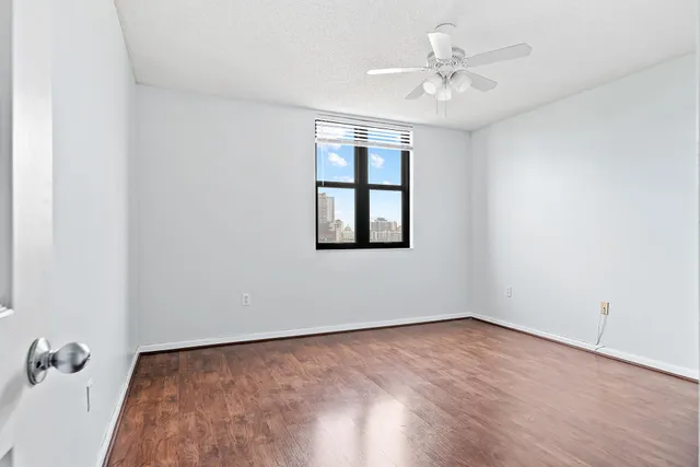 an empty room with a chandelier fan and windows