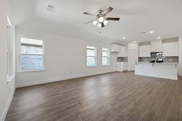 a view of an empty room with kitchen and window