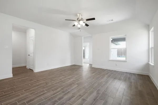 a view of an empty room with wooden floor and a window