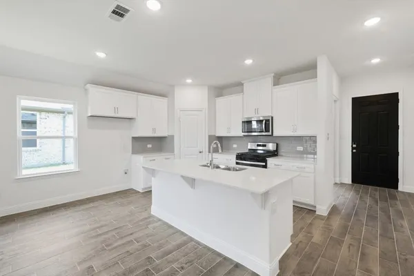 a kitchen with granite countertop a refrigerator stove top oven and sink