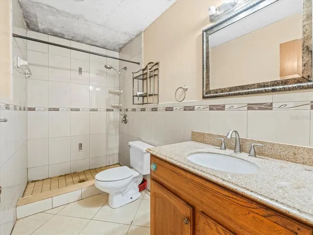 a bathroom with a granite countertop sink a toilet and a mirror
