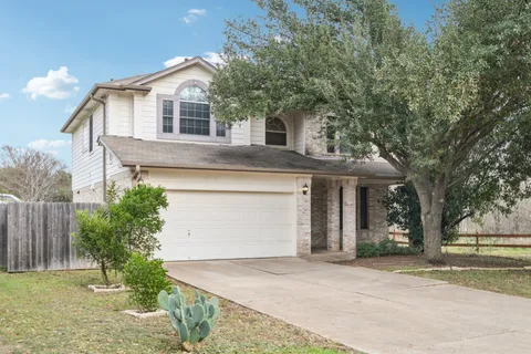a front view of a house with a garden and trees