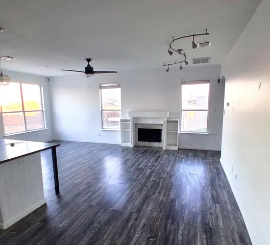 an empty room with wooden floor a fireplace and windows