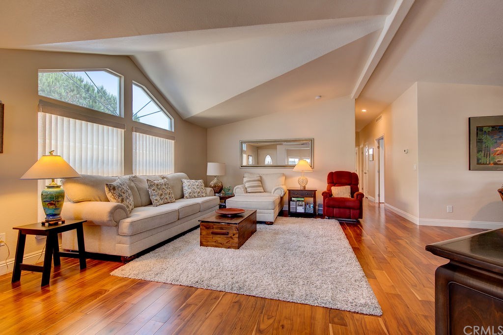 Look at this spacious living room and open concept with vaulted ceilings, big windows, and beautiful Acacia wood floors!