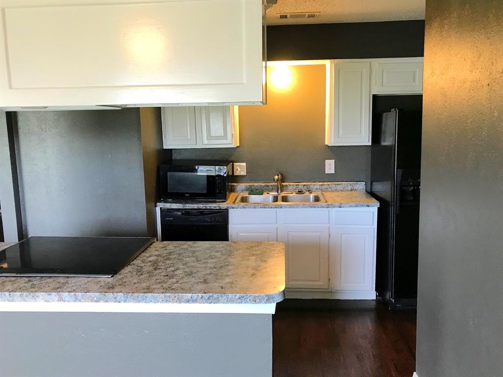 4023 William Street Sachse, TX 75048 - Photo 9 of 36 4023 Kitchen with light countertops, black appliances, dark wood-type flooring, and white cabinetry