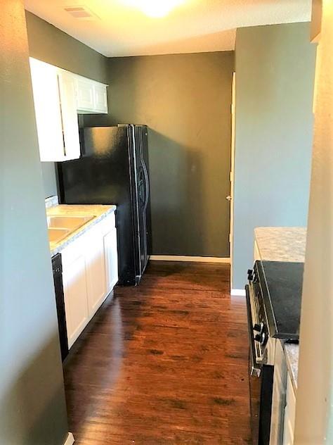 4023 William Street Sachse, TX 75048 - Photo 10 of 36 4023 Kitchen featuring white cabinets, dark wood-style flooring, stainless steel stove, and freestanding refrigerator