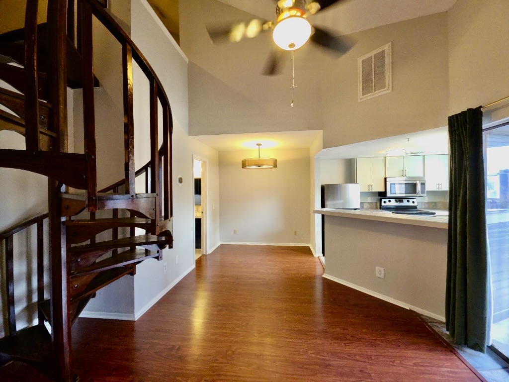 2500 Burleson Road, Unit 521 Austin, TX 78741 - Photo 6 of 20 Spiral staircase featuring dark wood-finish, high ceilings, wood-finish flooring, kitchen with stainless steel appliances, and a breakfast bar