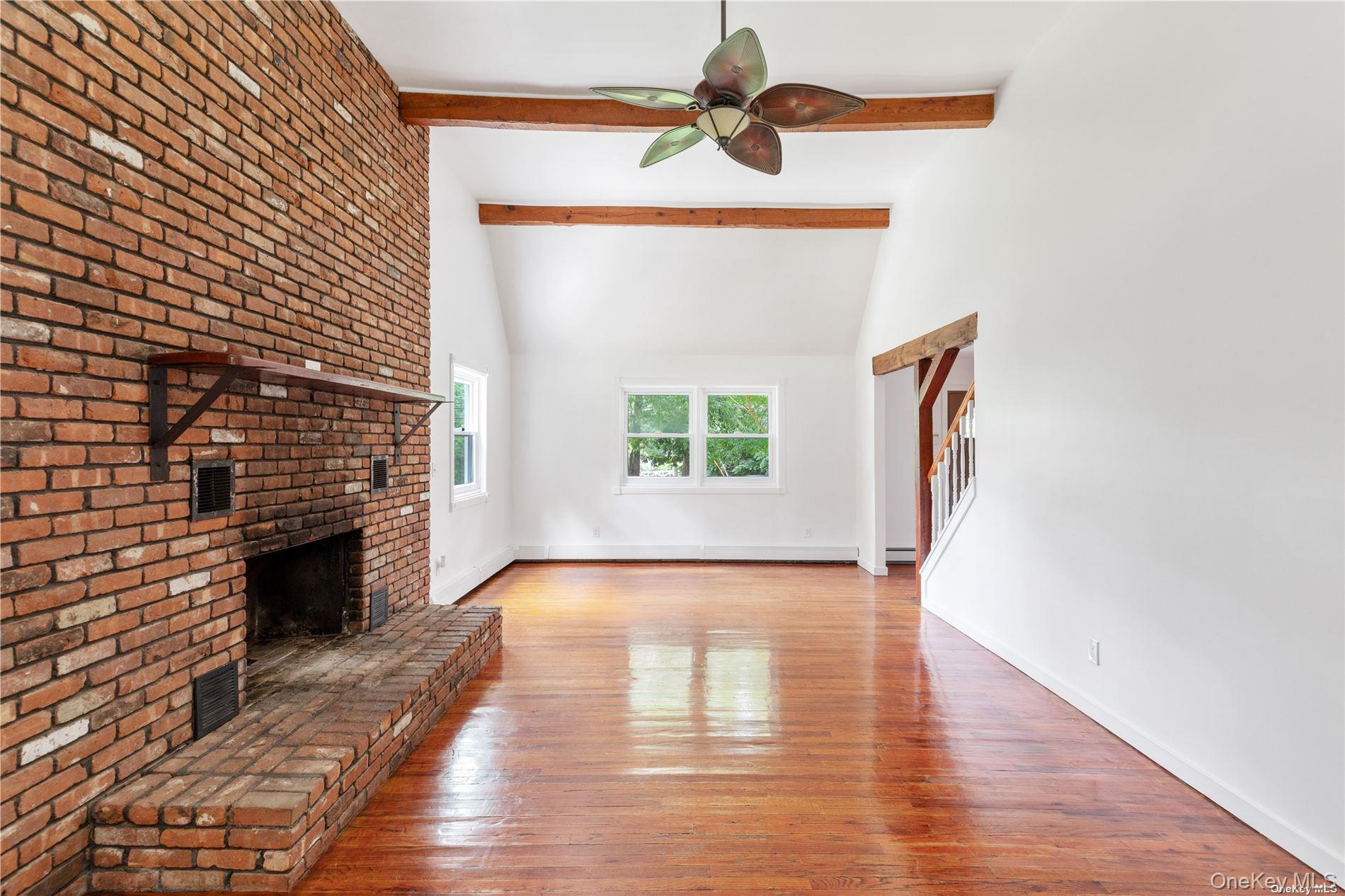 110 East Bartlett Road Middle Island, NY 11953 - Photo 7 of 29 an empty room with wooden floor fireplace and windows