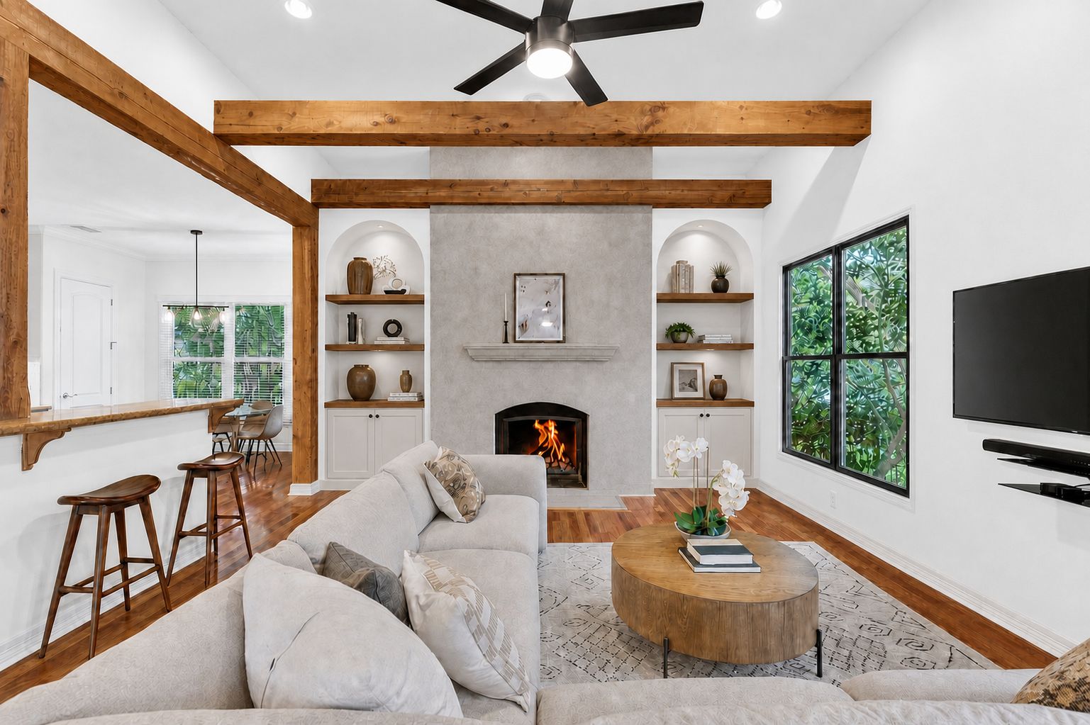 4110 Bunny Run, Unit 3 Austin, TX 78746 - Photo 8 of 35 VIRTUALLY ENHANCED FOR INSPIRATION - Living area featuring hardwood flooring, exposed ceiling beams, a stone fireplace, and large windows and glass-paneled doors providing natural light