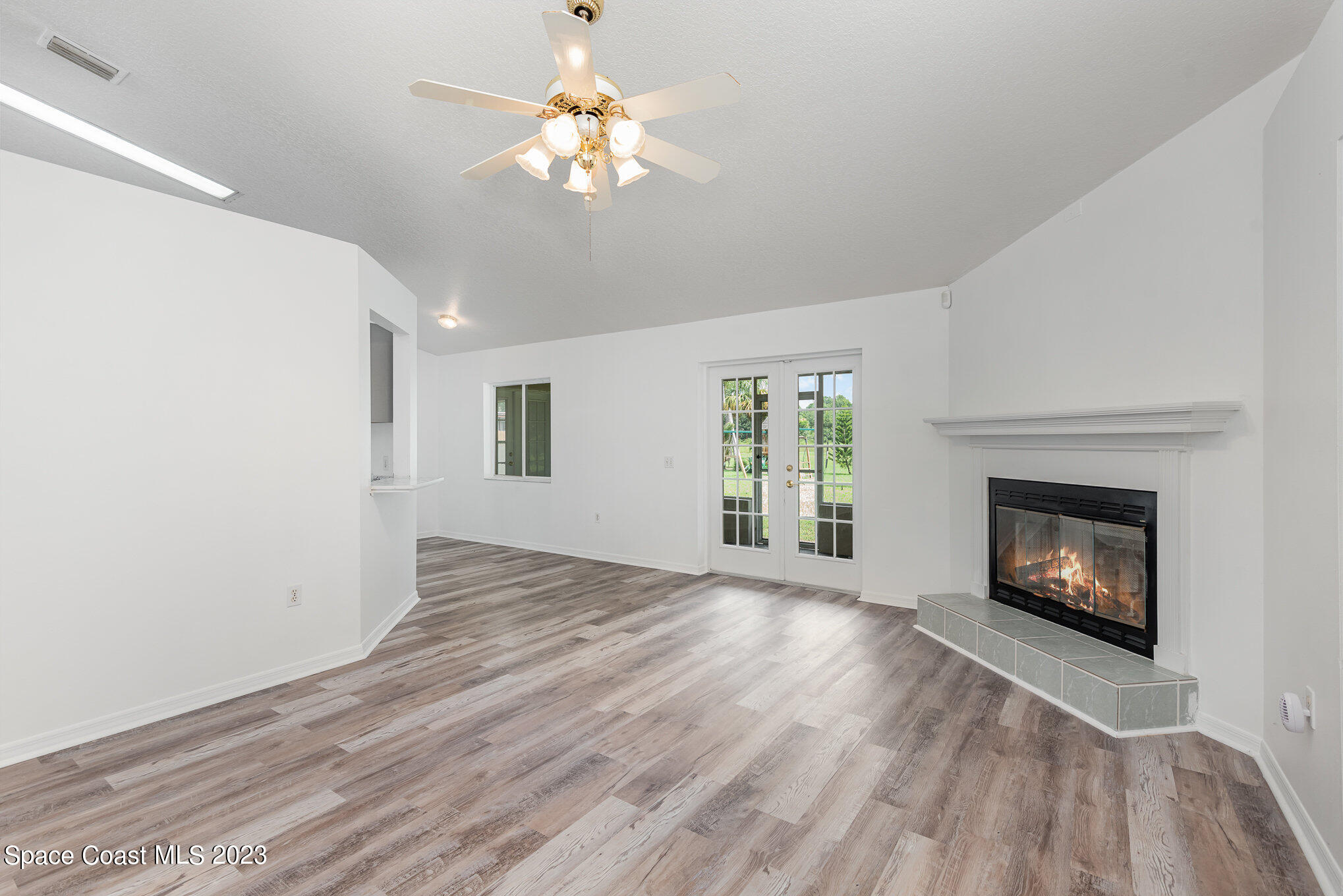 4390 London Town Road Titusville, FL 32796 - Photo 5 of 25 an empty room with windows fireplace and wooden floor