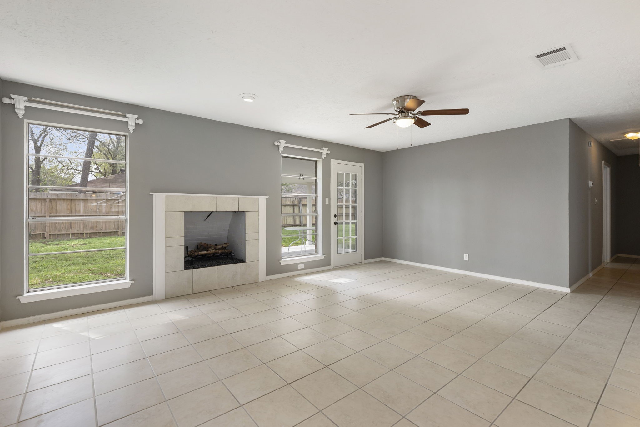 29107 Binefield Street Spring, TX 77386 - Photo 3 of 18 SPACIOUS and inviting gathering space featuring a decorative (de-commissioned) fireplace, large windows for abundant natural light, ceiling fan, and glass door opening to the covered patio and backyard.
