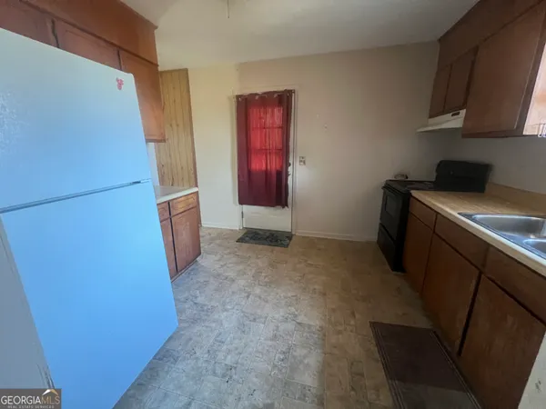 a view of a utility room with fridge and wooden floor