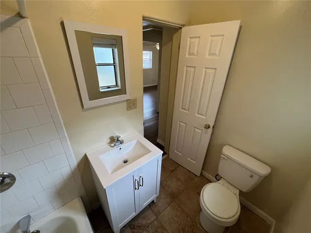 a bathroom with a granite countertop toilet sink and mirror