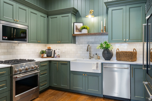 115 East Hidden Ridge Lane, Unit 42 Mapleton, UT 84664 - Photo 60 of 103 Kitchen featuring custom green cabinetry, white subway tile backsplash, white countertop, stainless steel appliances, and a farmhouse sink with a brass faucet
