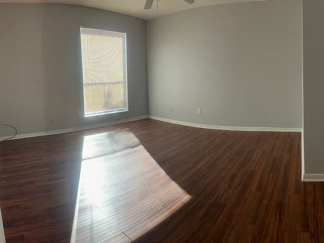 an empty room with wooden floor and windows