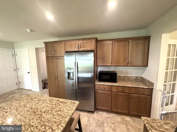 a kitchen with stainless steel appliances kitchen island granite countertop a refrigerator and a sink