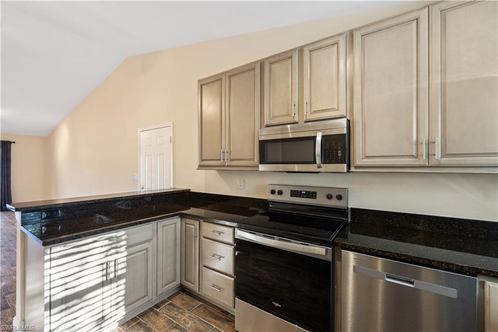 2142 Arbour Walk Circle, Unit 2626 Naples, FL 34109 - Photo 5 of 20 a kitchen with stainless steel appliances granite countertop white cabinets and black granite counter tops