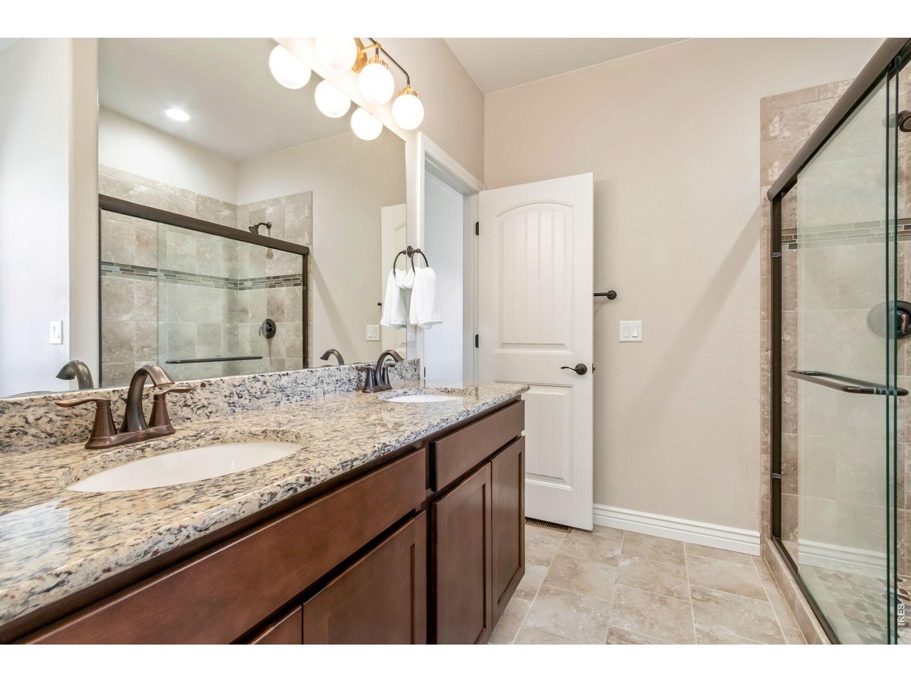 5531 Teeling Court Timnath, CO 80547 - Photo 21 of 48 a bathroom with a granite countertop sink a mirror and a shower