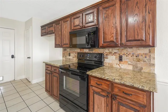 a kitchen with granite countertop a stove top oven microwave and cabinets