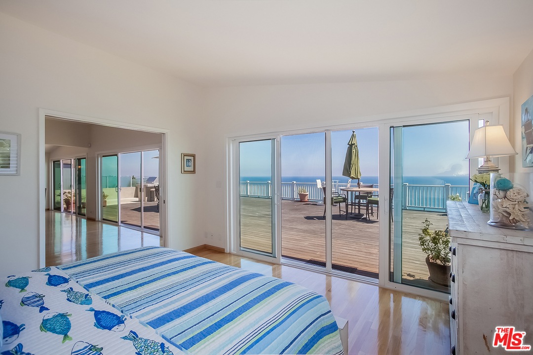 18440 Coastline Drive Malibu, CA 90265 - Photo 12 of 21 a bedroom with a bed and walk in closet with wooden floor