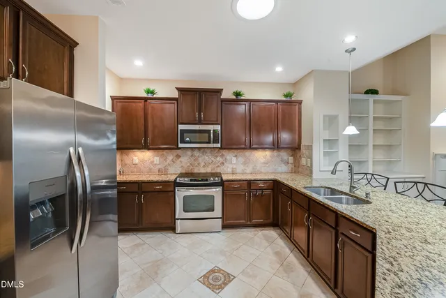 a kitchen with stainless steel appliances granite countertop a sink stove and refrigerator