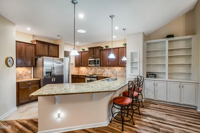 a kitchen with stainless steel appliances granite countertop a stove a sink and a refrigerator