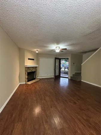 an empty room with wooden floor fire place and refrigerator