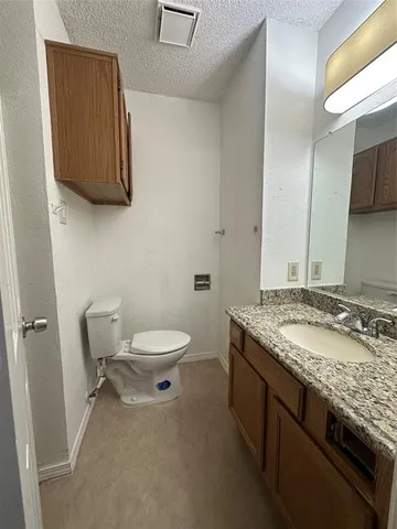 a bathroom with a granite countertop toilet sink and mirror