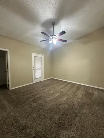 an empty room with a chandelier fan and windows