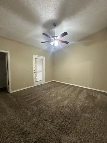 an empty room with a chandelier fan and windows